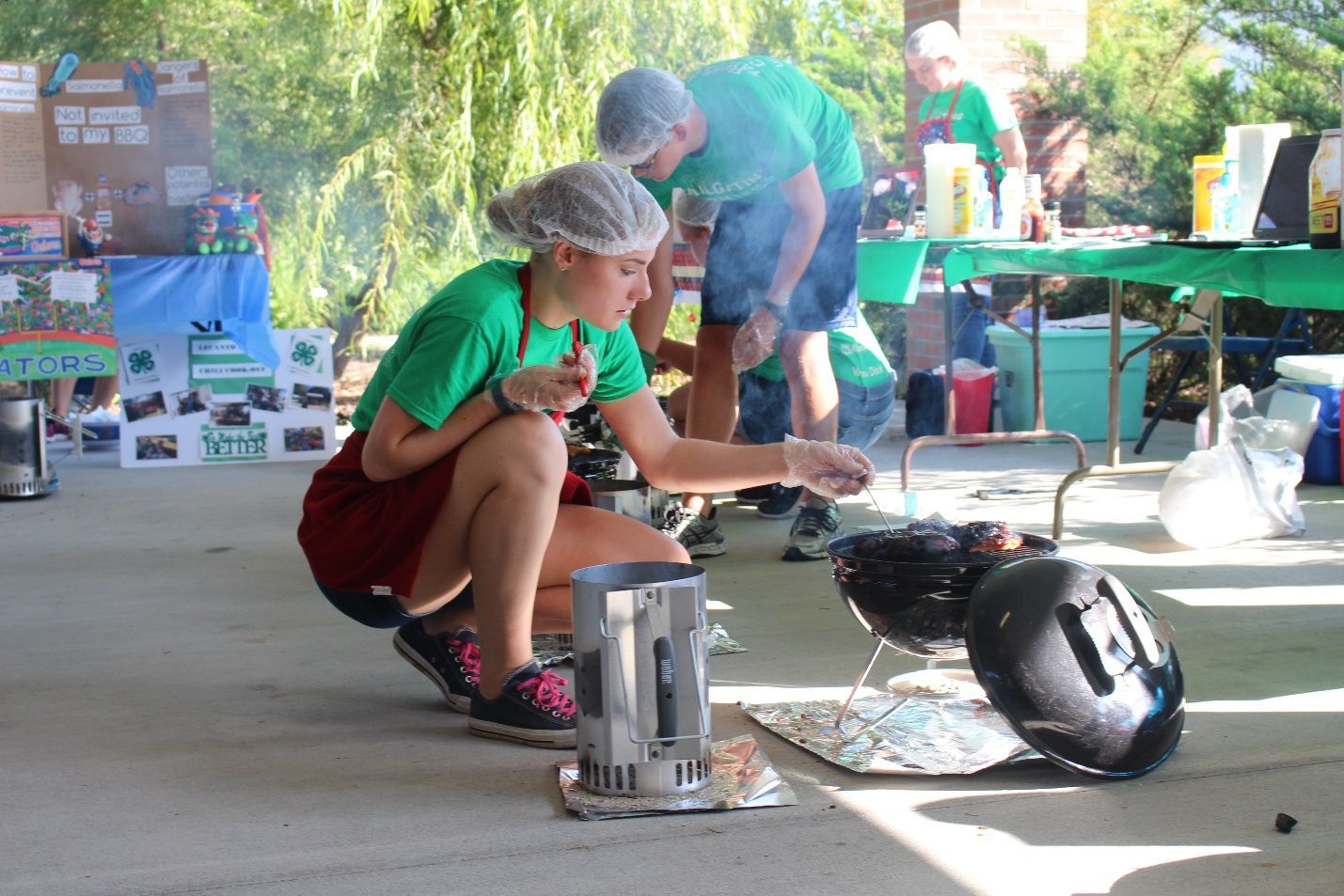 4-Her kneels to check the temperature of her meat on the grill
