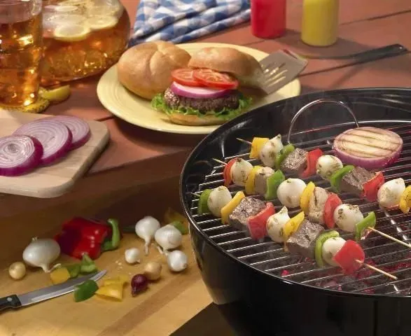 Figure 1. Artful arrangement of various foods for an outdoor meal including a picnic table, two cutting boards and a charcoal grill.